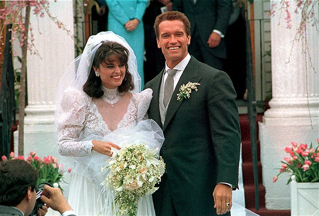 Na archívnej snímke z 25. apríla 1986 novomanželia Maria Shriverová (vľavo) a ženích Arnold Schwarzenegger pózujú po svadobnom obrade pred kostolom St. Francis Xavier v meste Hyannis.
