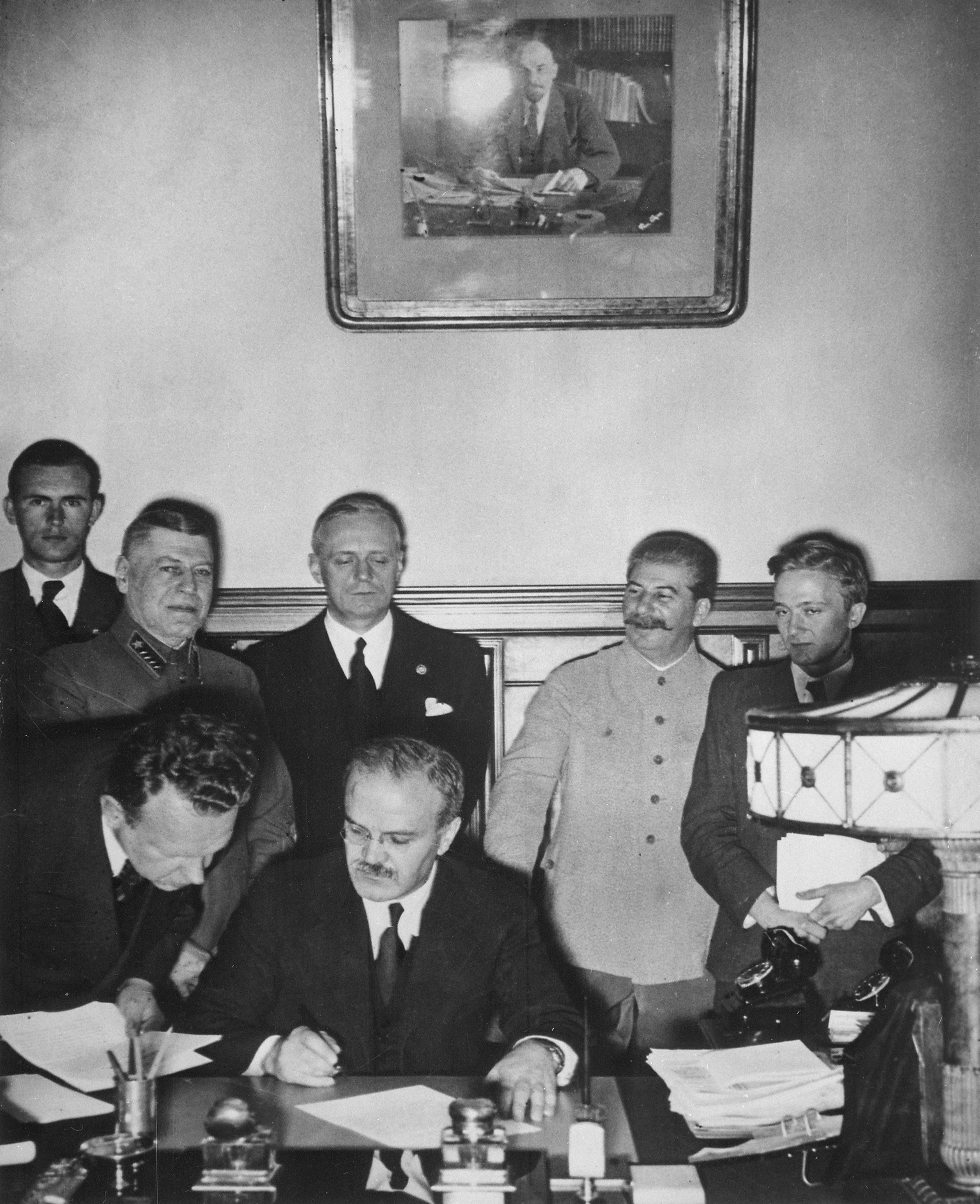 Podpis druhého tajného dodatku paktu Molotov–Ribbentrop v Kremli 28. septembra 1939 (Zmluva o neútočení a jej prvý tajný dodatok medzi Nemeckom a ZSSR boli podpísané už 23. augusta 1939). Viačeslav Molotov podpisuje dodatok, za ním stojí Joachim von Ribbentrop, napravo je Josif Stalin.