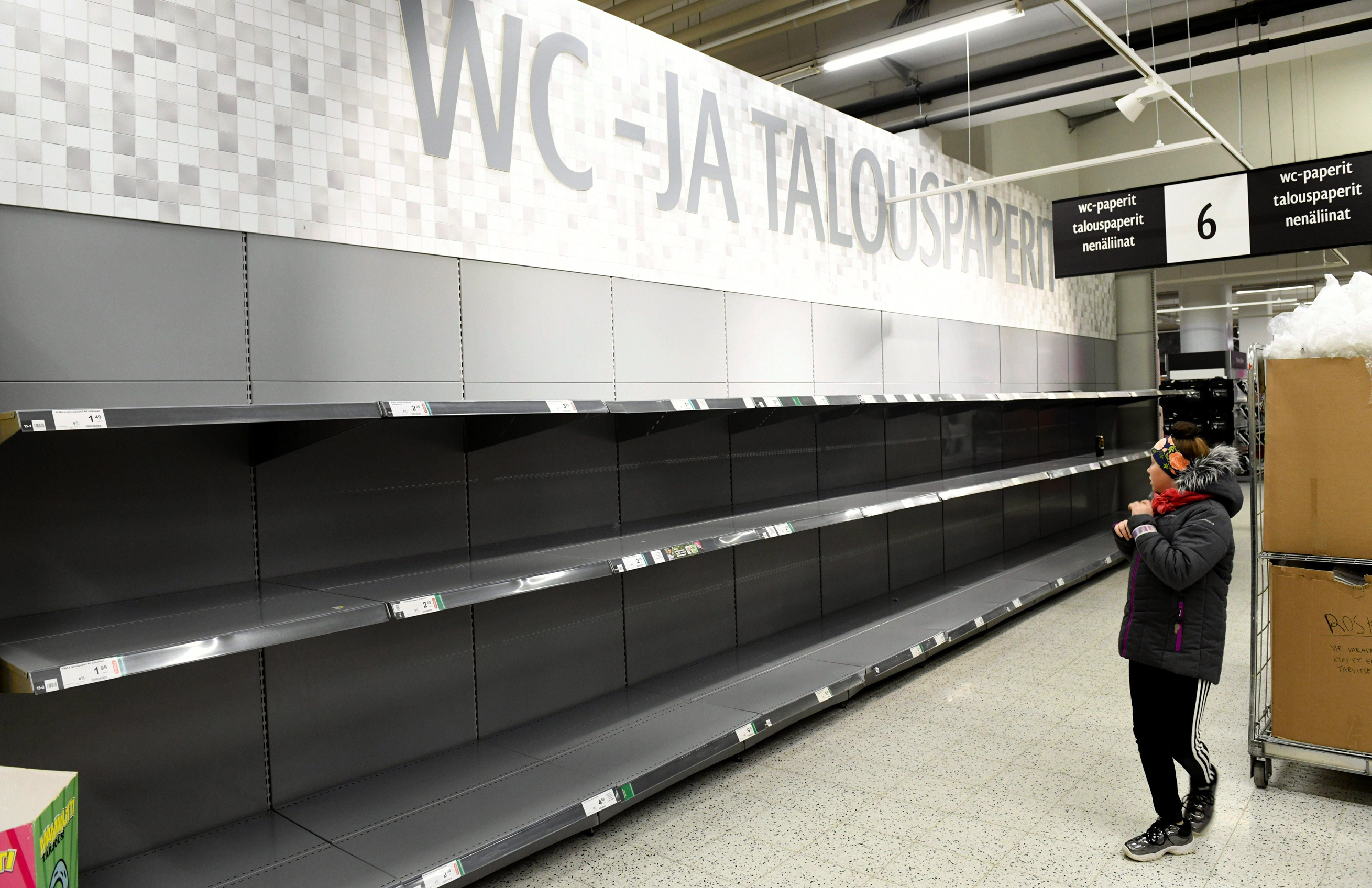 Chlapec v Helsinkách sa pozerá na úplne prázdne regály s toaletným papierom v supermarkete.