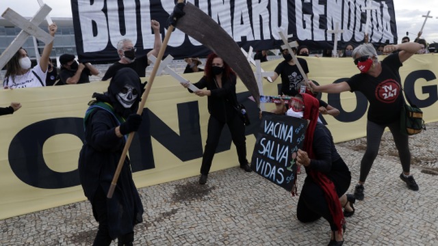 Demonštrant drží transparenty s nápismi v portugalčine "Očkovanie zachraňuje životy (dole)" a "Bolsonaro genocída" počas protestu proti brazílskemu prezidentovi Jairovi Bolsonarovi.