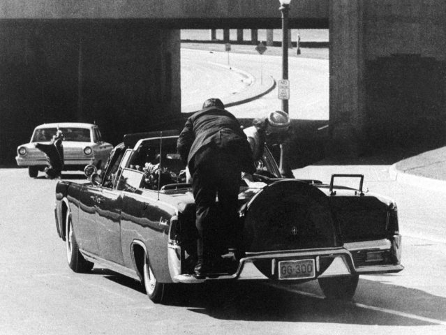 Na archívnej snímke z 22. novembra 1963 prezident John F. Kennedy padá na zadnom sedadle prezidentskej limuzíny, ktorá sa rúti po Elm Street v Dallase po tom, ako bol smrteľne postrelený. Prvá dáma Jacqueline Kennedyová sa skláňa nad prezidentom, zatiaľ čo ju agent tajnej služby Clint Hill tlačí späť na sedadlo.