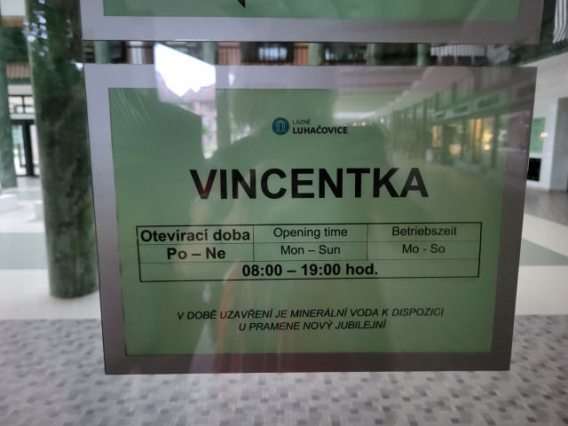 Tabuľa na dverách do haly Vincentka s odrazom kolonády na skle.